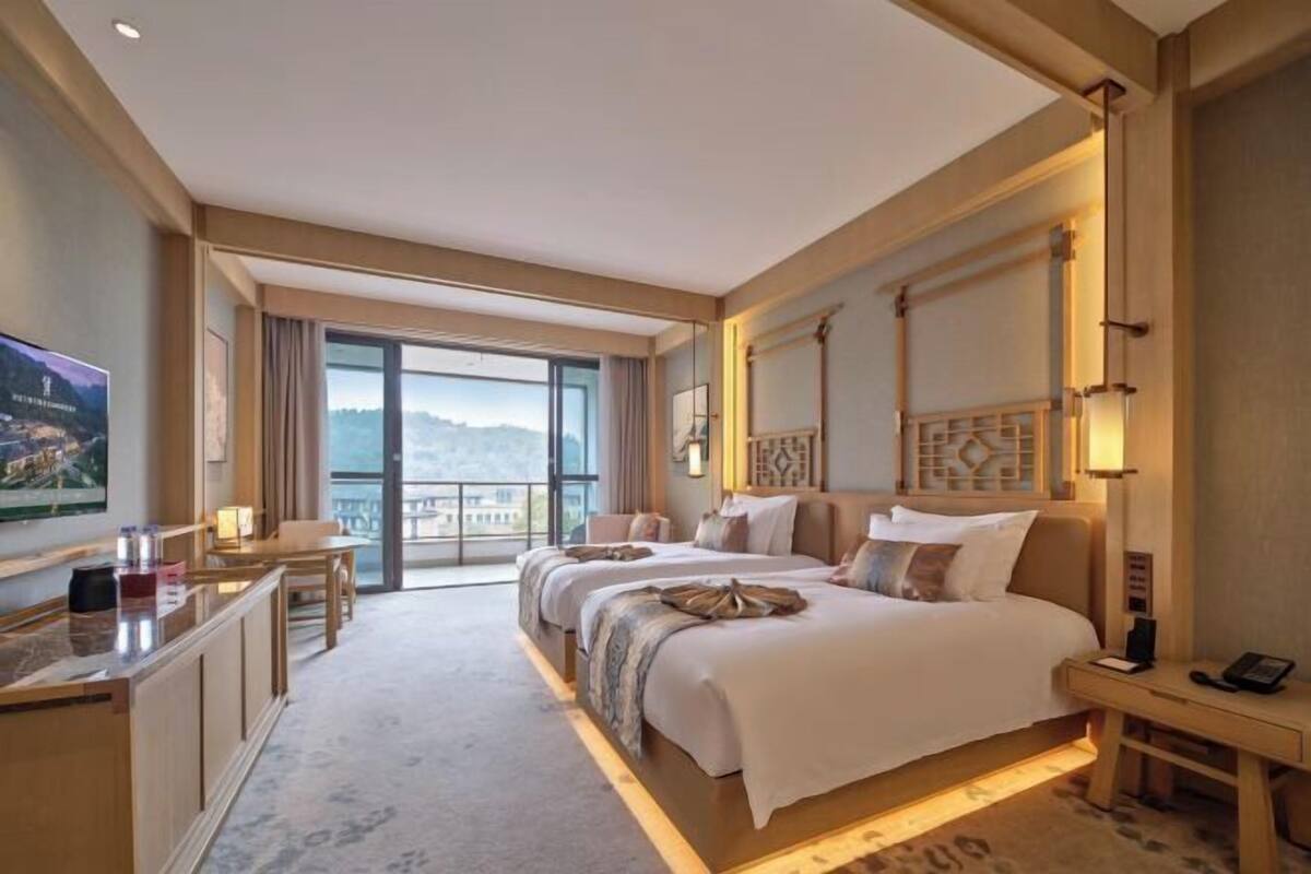 Een hotelkamer met een groot bed, een bureau, een stoel en uitzicht op het omliggende landschap.