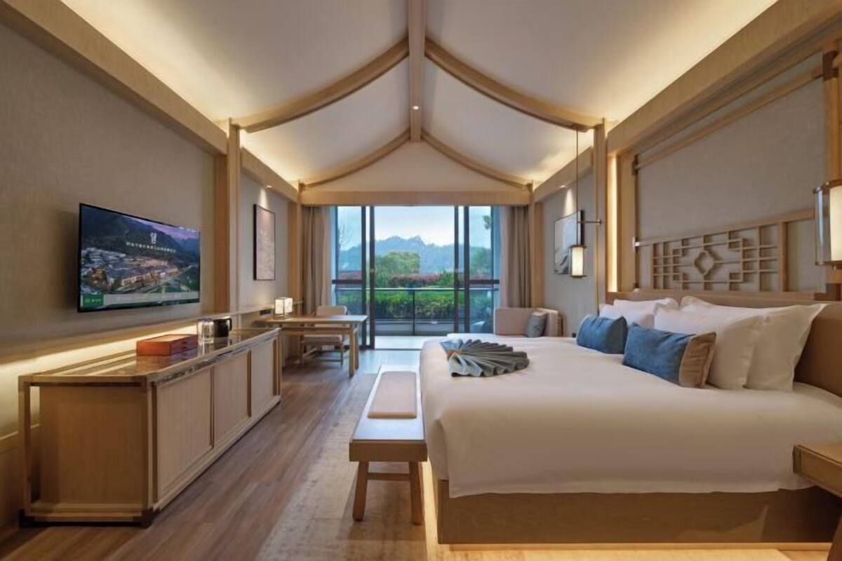 Een hotelkamer met een bed, een televisie, een bureau en een balkon met uitzicht.