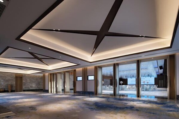 Un hall d’hôtel spacieux, doté d’un plafond au design moderne, de grandes fenêtres et d’un sol en marbre.