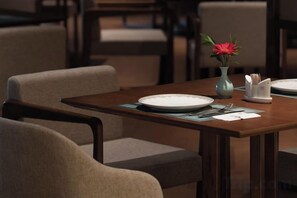 A dining table with plates, cutlery, and a vase with a flower. - YunXi DengYun Resort Hotel (Xianju)