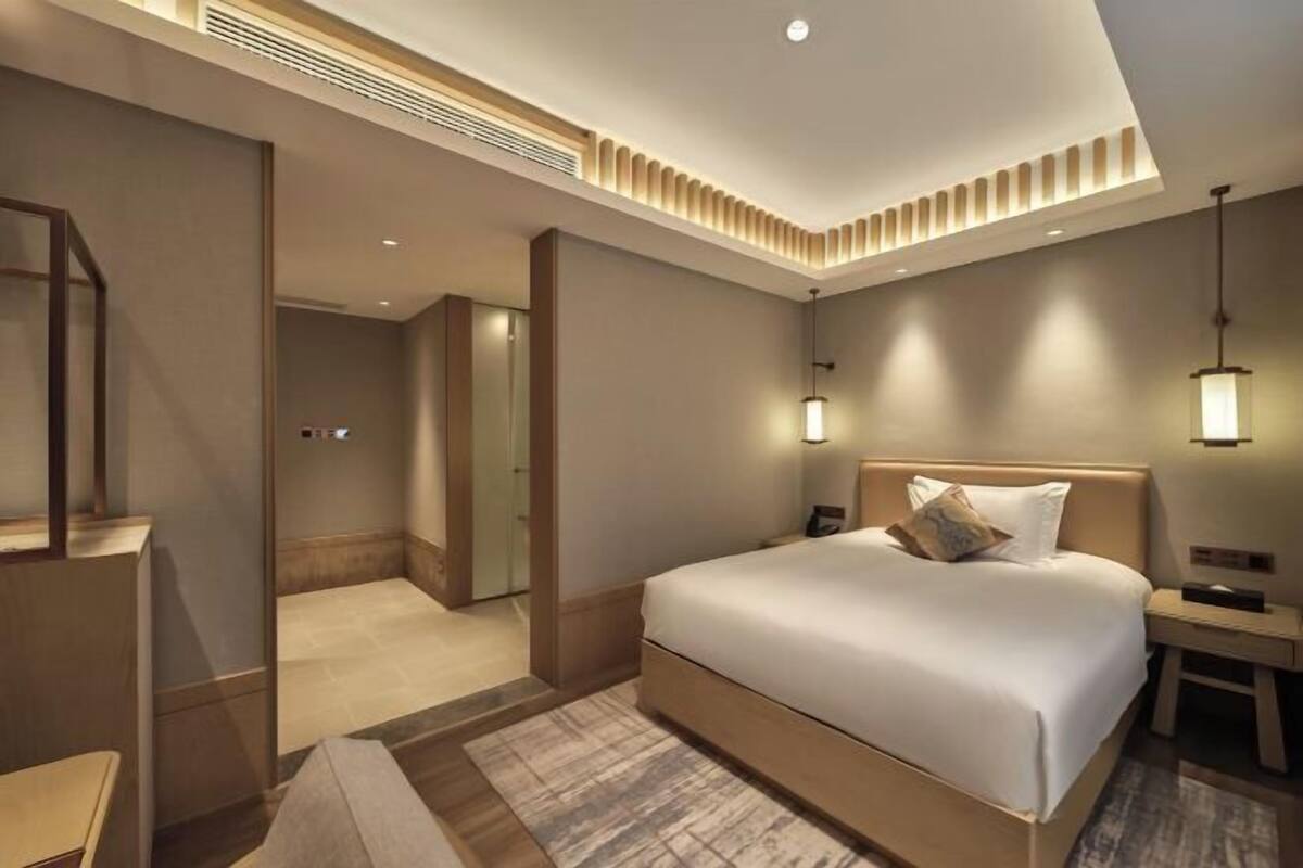 Een moderne hotelkamer met een groot bed, nachtkastjes, een spiegel en een inloopkast.