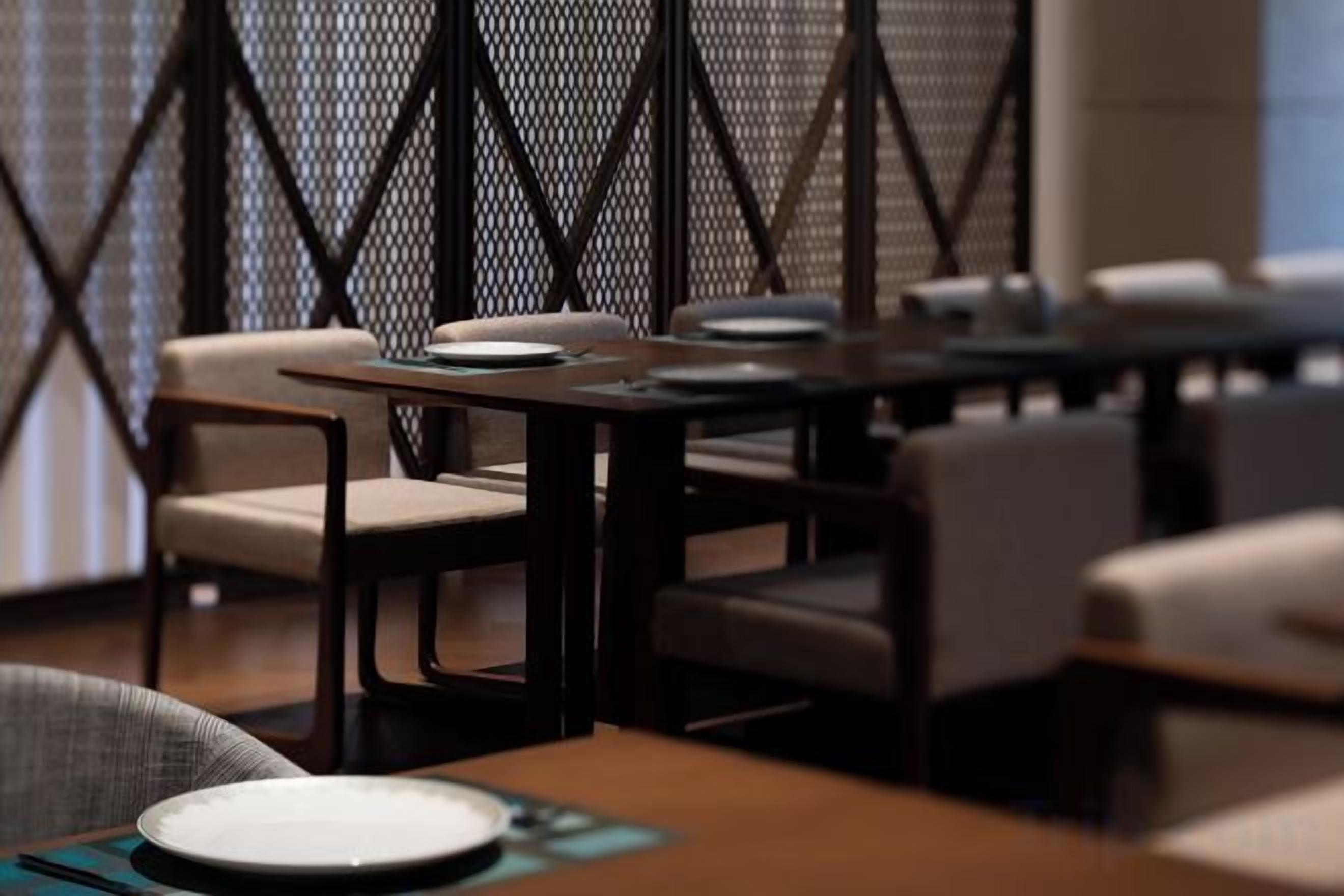 Een restaurant met tafels, stoelen, een behangetabel en een raam.