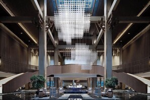 Un hall d’entrée spacieux agrémenté d’un grand lustre moderne, d’une fontaine centrale et de plusieurs espaces aménagés pour s’asseoir.