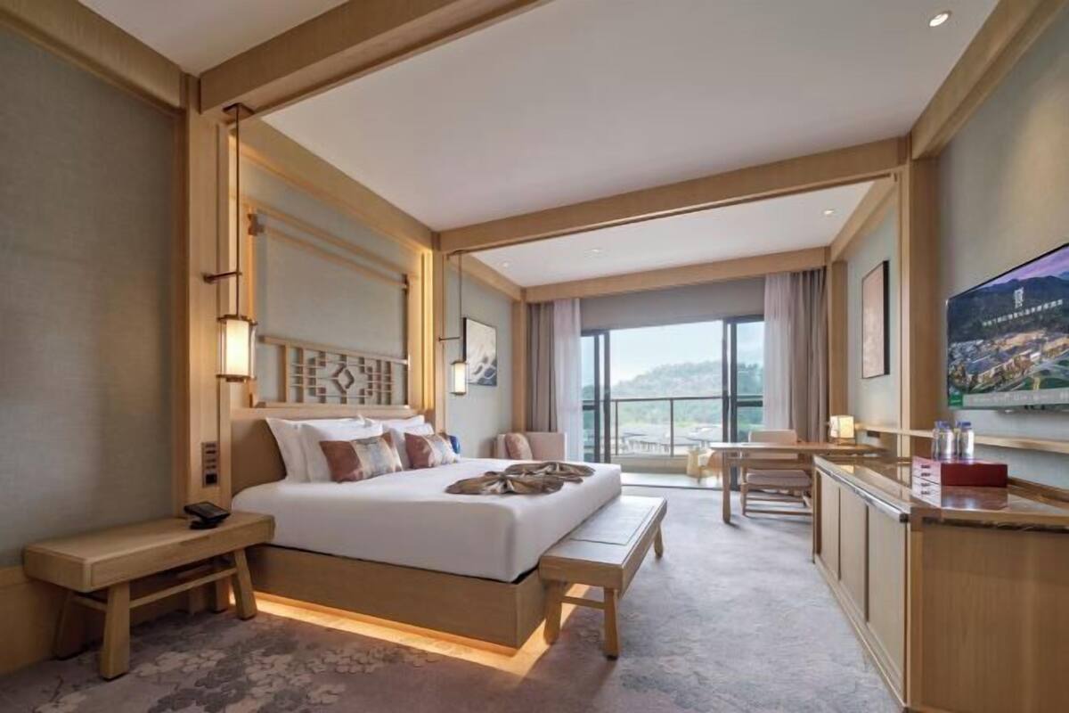 Een hotelkamer met een groot bed, nachtkastjes, een bureau en een televisie.