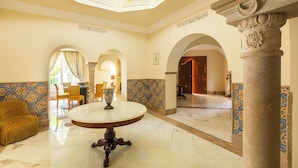 A spacious lobby with a marble floor, a round table, and a yellow armchair. - Nawara Residence (La Marsa)