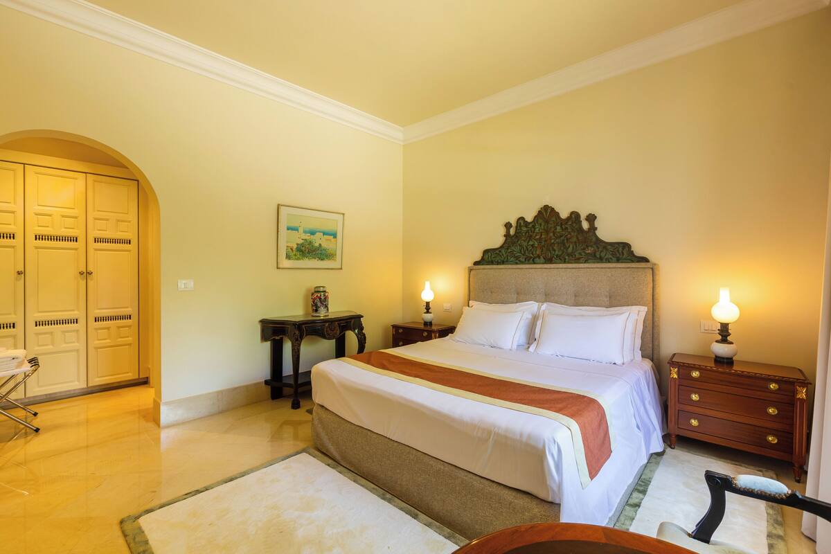 Una habitación de hotel con una cama grande, una mesita de noche de madera, un escritorio y una silla.
