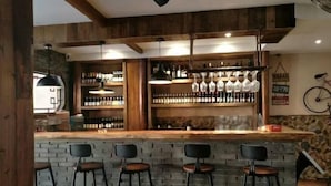 Een bar met houten balken, een bakstenen muur en een toonbank met krukken.