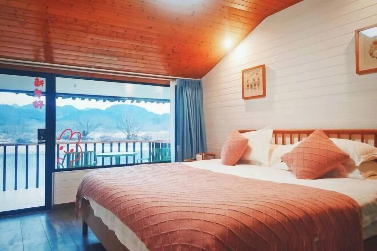 Una camera da letto con un letto, una finestra vista e un soffitto in legno.