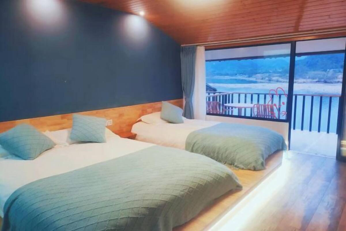 Una camera da letto con due letti, un balcone e vista panoramica, e un soffitto in legno.