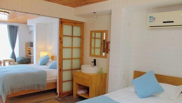 A bedroom with two beds, a wooden bedside table, a mirror, and an air conditioning unit. - Guyan Huaxiang Jiangnan Hostel (Lishui)