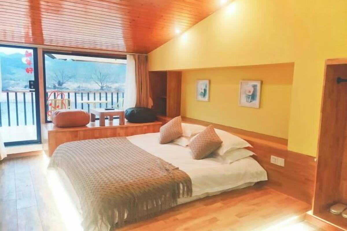 Una camera da letto con un letto, pavimento in legno, una finestra vista e una porta.