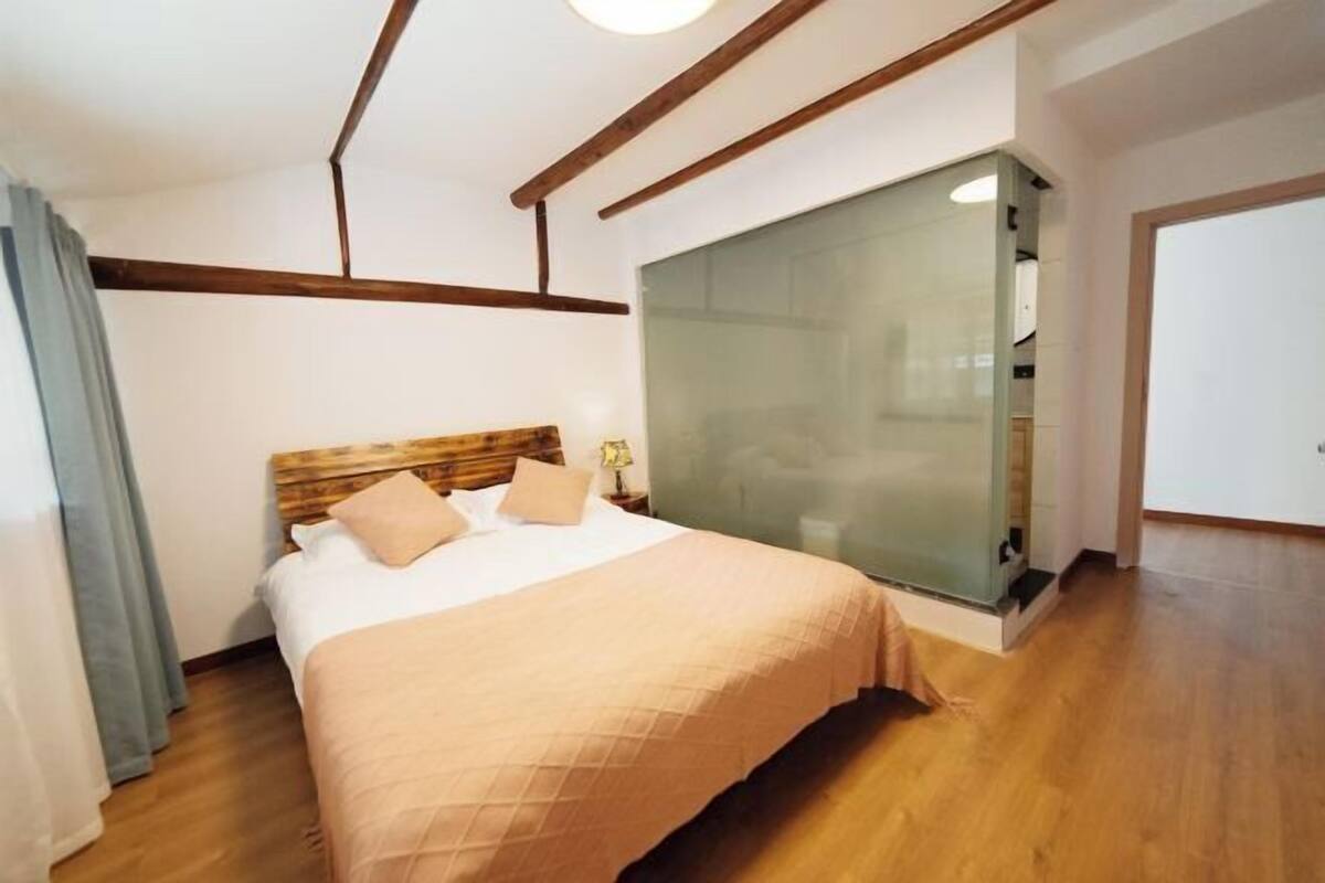Una camera da letto con un letto, una testiera in legno e un divisorio in vetro.