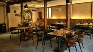 Een restaurant met houten tafels en stoelen, een muurschildering en een houten plafondconstructie.