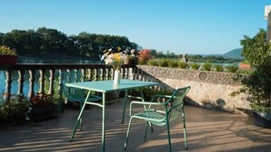 An outdoor patio with a table and chairs, overlooking a body of water and greenery. - Guyan Huaxiang Jiangnan Hostel (Lishui)