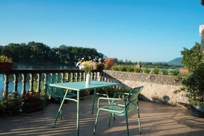 An outdoor patio with a table and chairs, overlooking a body of water and greenery. - Guyan Huaxiang Jiangnan Hostel (Lishui)
