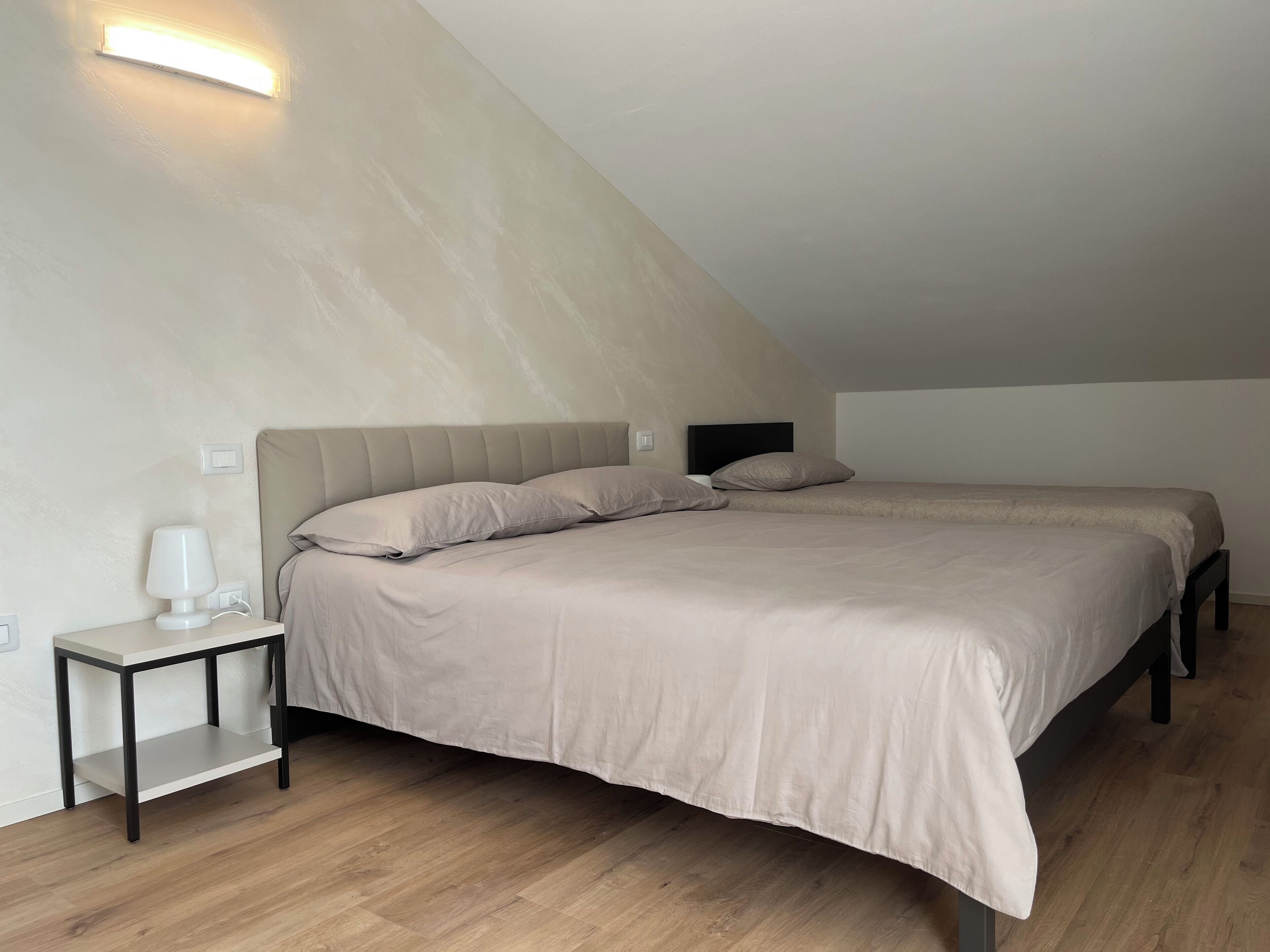 Une chambre à coucher avec un grand lit, une table de chevet et un luminaire fixé au mur.