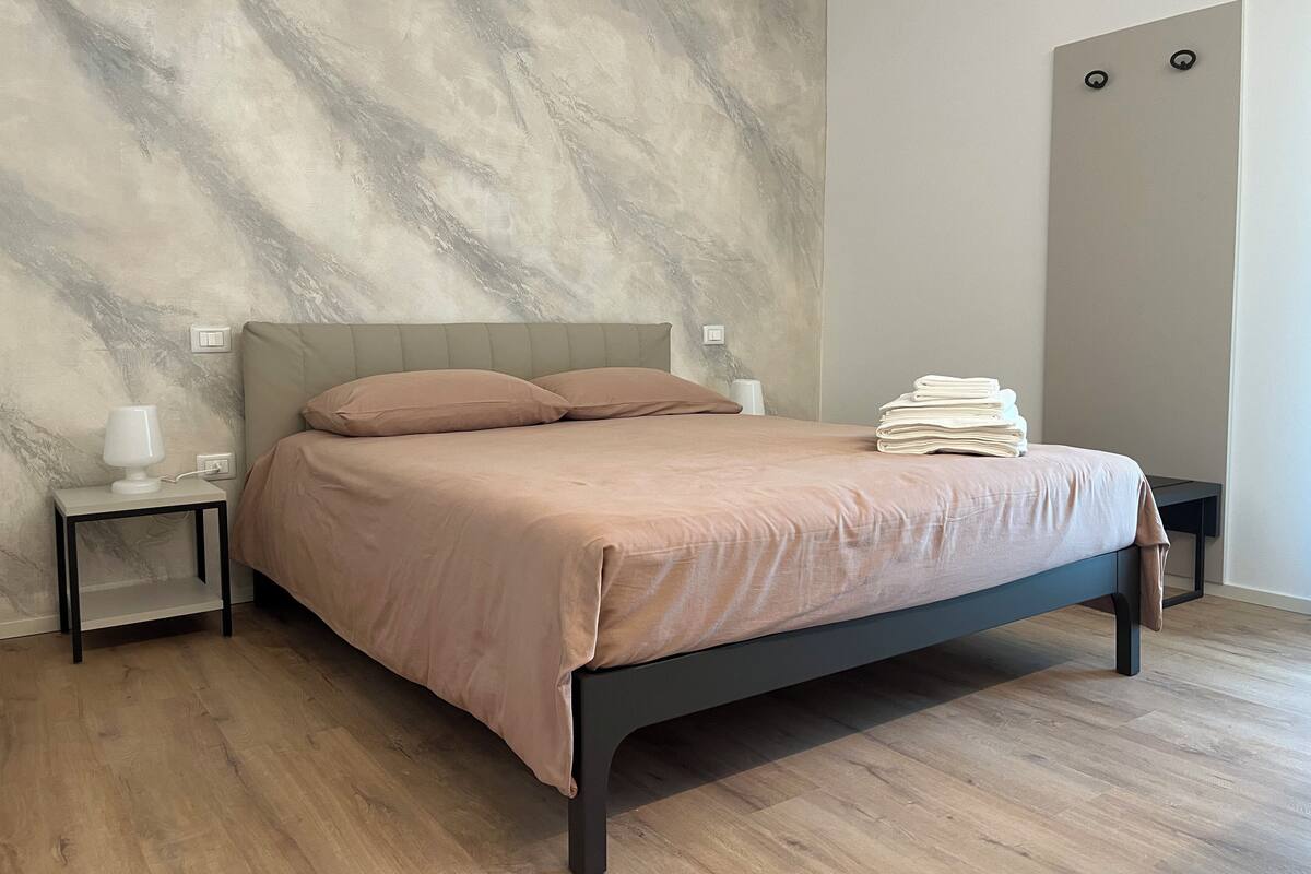 Une chambre à coucher avec un lit, des tables de chevet et un mur dont la texture rappelle celle du marbre.