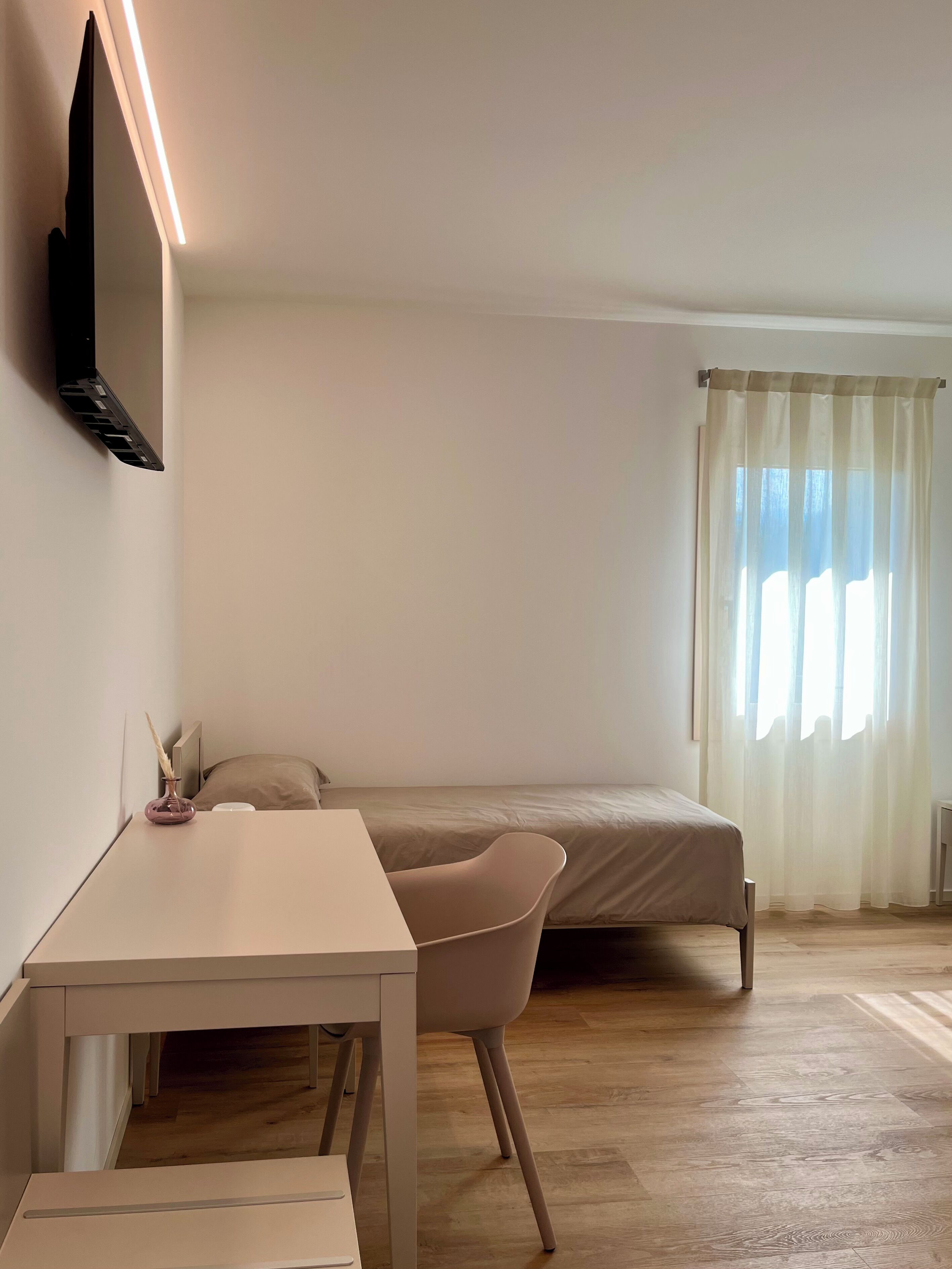 Een minimalistisch ingerichte kamer met een bed, bureau en stoel.