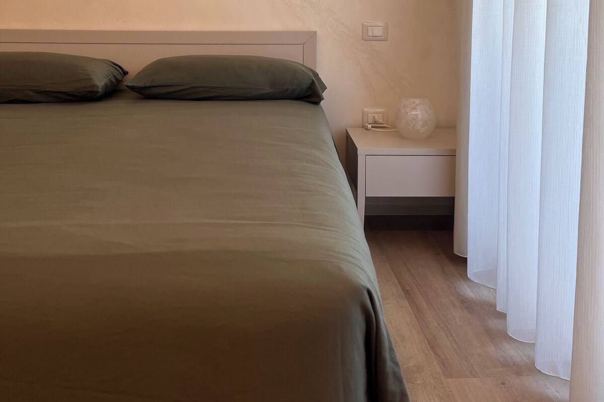 Une chambre à coucher avec un lit, une table de chevet et des rideaux.