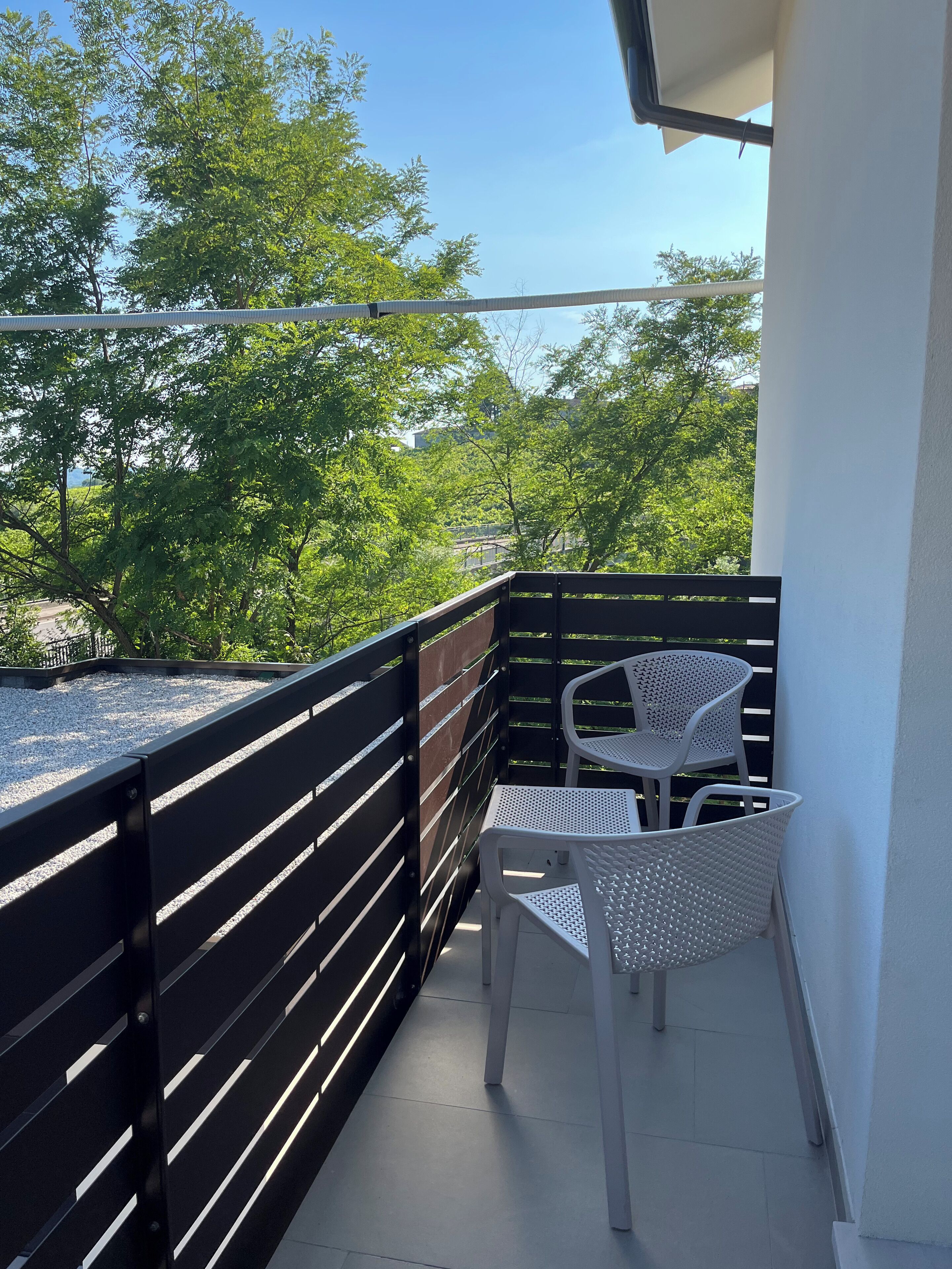 A balcony with a black railing, a white table, and a white chair.