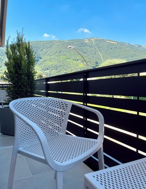 A white perforated chair on a balcony with a view of green hills and a clear sky. - Alle Colline (Valdobbiadene)