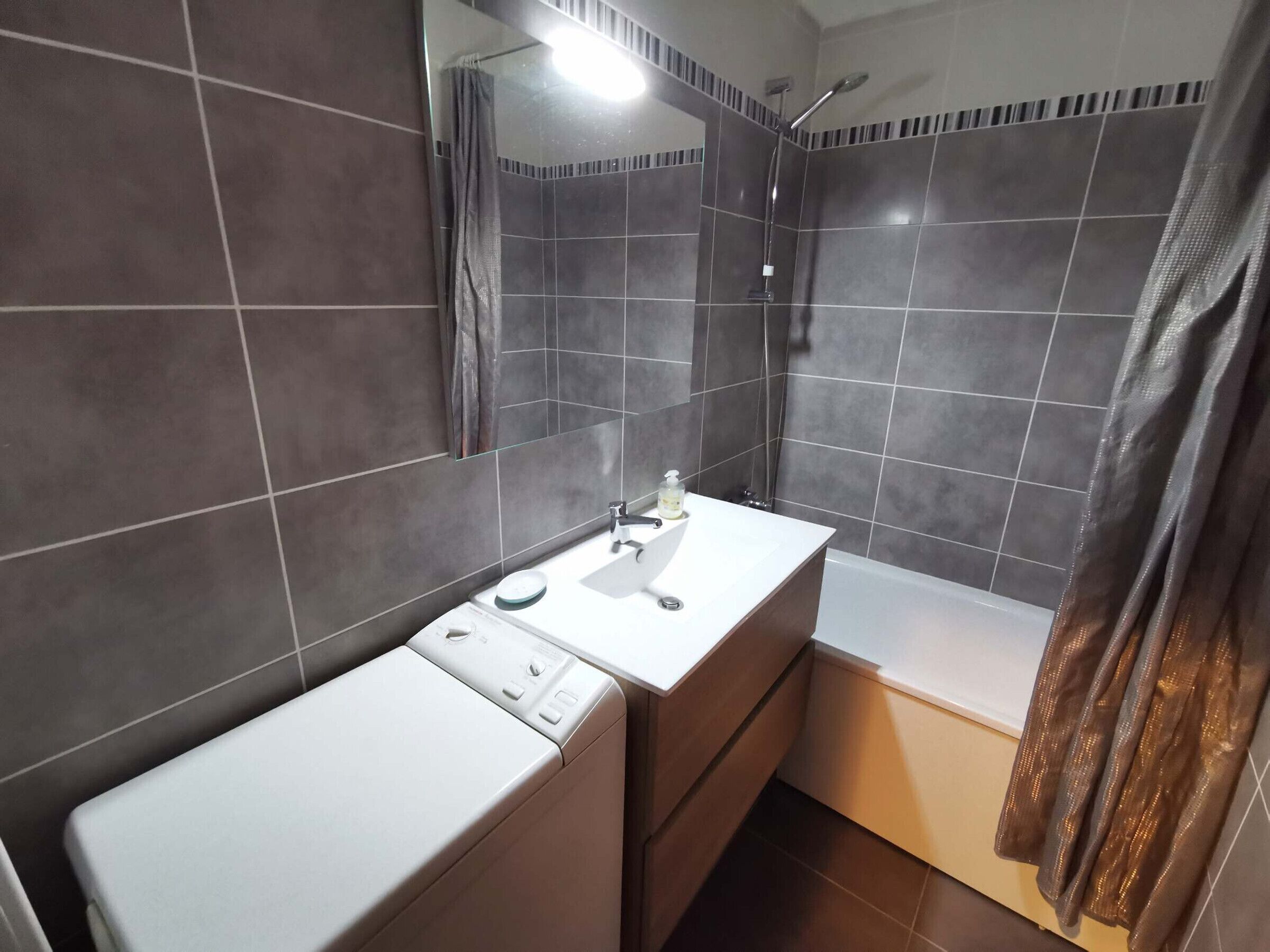 A modern bathroom with a white sink, mirror, and a shower area.