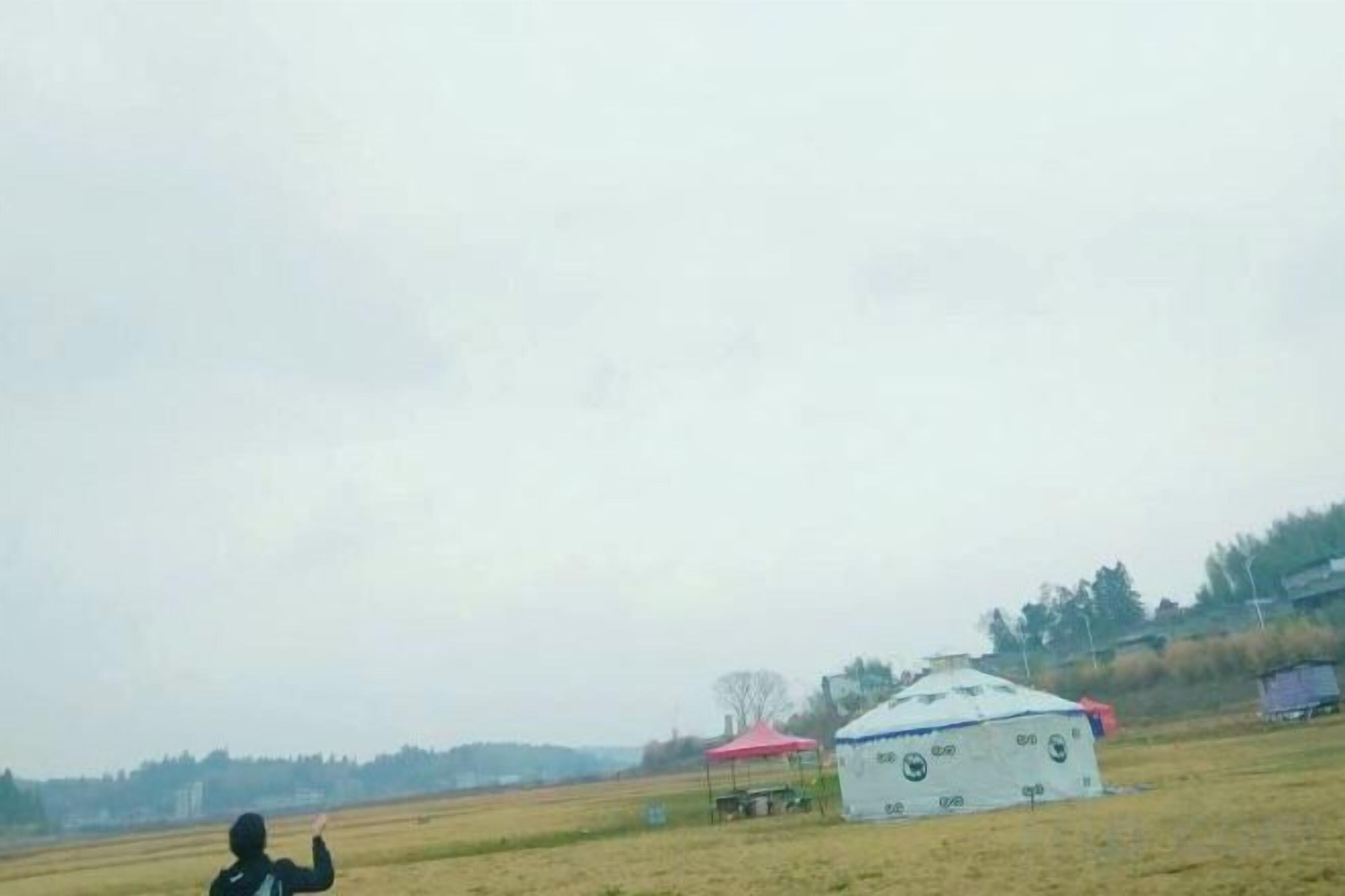 A tent-like structure in an open field with a clear sky.