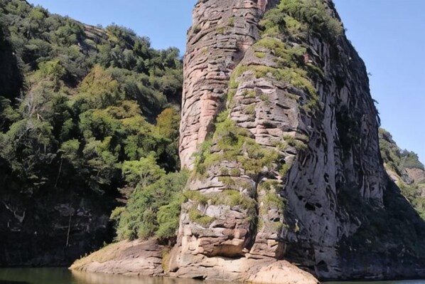 A natural rock formation with a narrow base and a steep, vertical face. - Taining Luxiang Nanhui Hotel (Jinhu Prairie) (Taining)