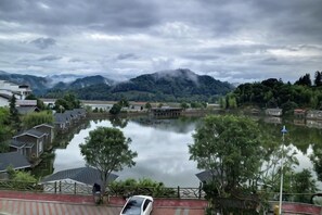 A calm lake with buildings and trees in the foreground, and mountains in the background. - Taining Luxiang Nanhui Hotel (Jinhu Prairie) (Taining)