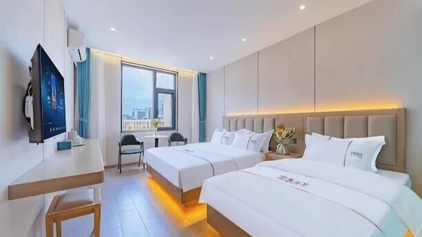 A hotel room with two beds, a desk, a TV, and a window with a view. - Taining Luxiang Nanhui Hotel (Jinhu Prairie) (Taining)