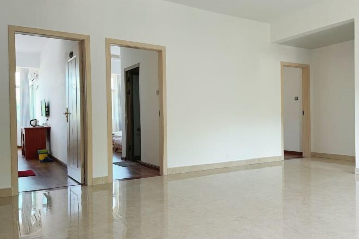 Una habitación amplia y vacía con piso pulido, una puerta que da a otra estancia y un marco de puerta visible.