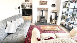 Una sala de estar con un sofá gris, televisor, chimenea y estantería.