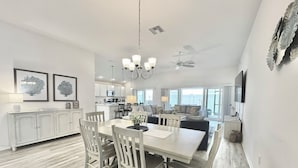 A modern kitchen with white cabinets, a dining area with a white table and chairs, and a ceiling fan. - Lost Shaker of Salt - 3/3 w/ 4-Seater Golf Cart in Moultrie Creek, The Villages! (The Villages)