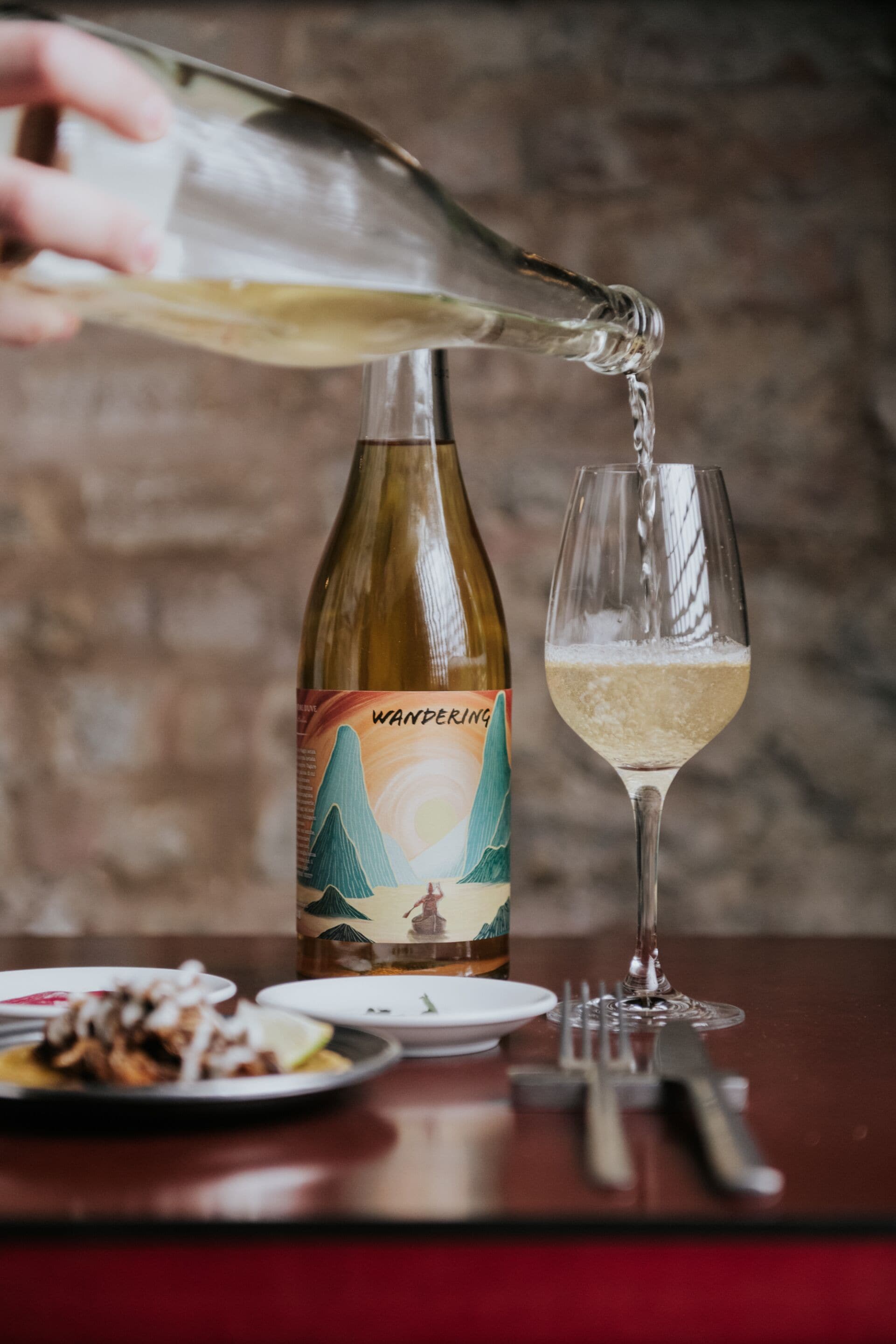 A bottle of wine being poured into a glass.