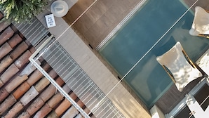 Luchtbeeld van een dakterraszwembad met twee personen, een pergola en zonnepanelen.