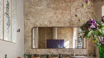 Un comedor con mesas y sillas de madera, un muro de piedra y un espejo grande.