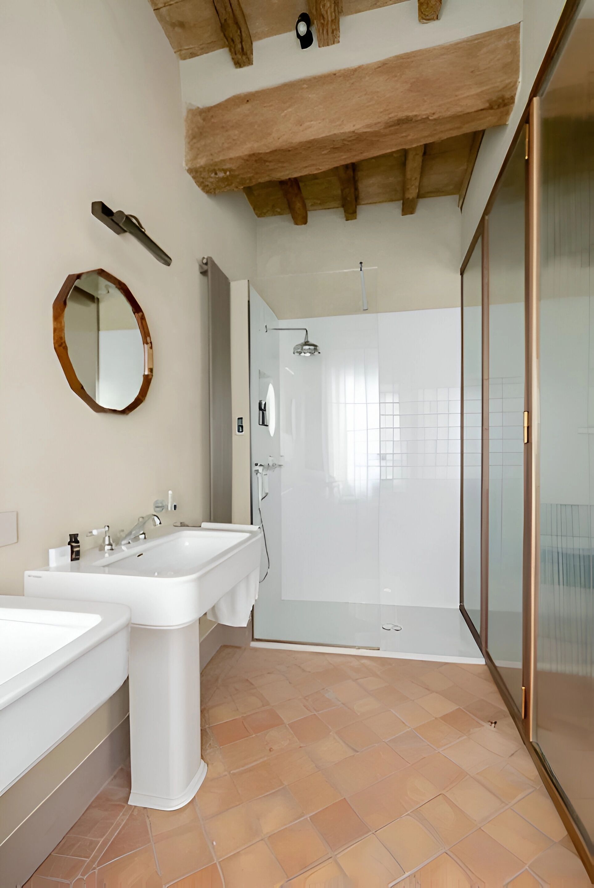 Une salle de bain moderne avec deux lavabos, une douche et un espace de douche séparé par des parois en verre.