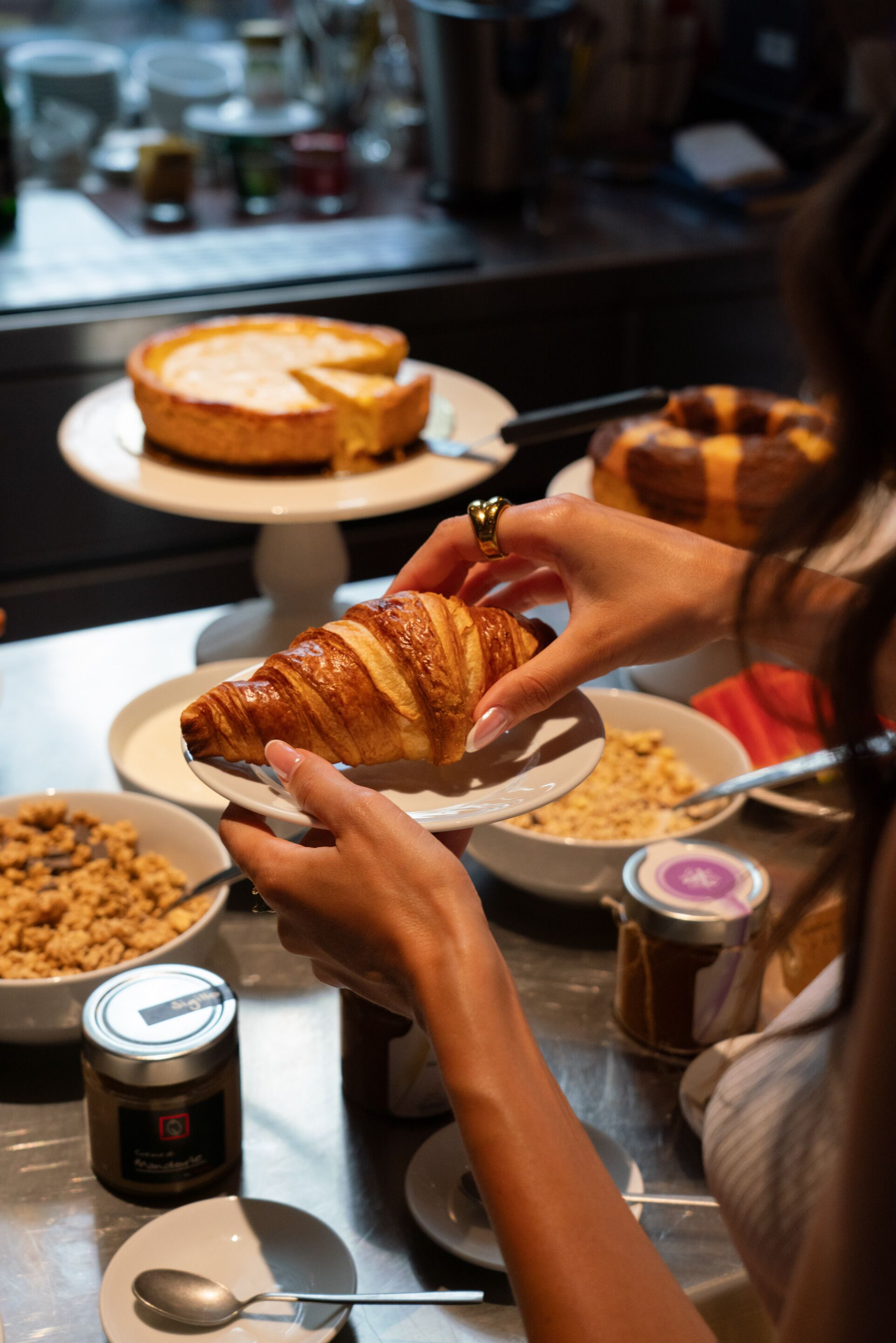 Ruokapöytä, jonka päällä on erilaisia ruoka-aineita, ja tarjoilussa on croissant.