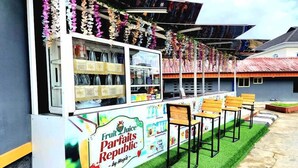 Un puesto de comida llamado 'Fruit Juice Parfaits Republic', con un cartel, recipientes de vidrio y sillas de madera.