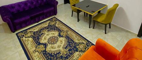 Una sala de estar con un sofá púrpura, una mesa amarilla y un sillón naranja.