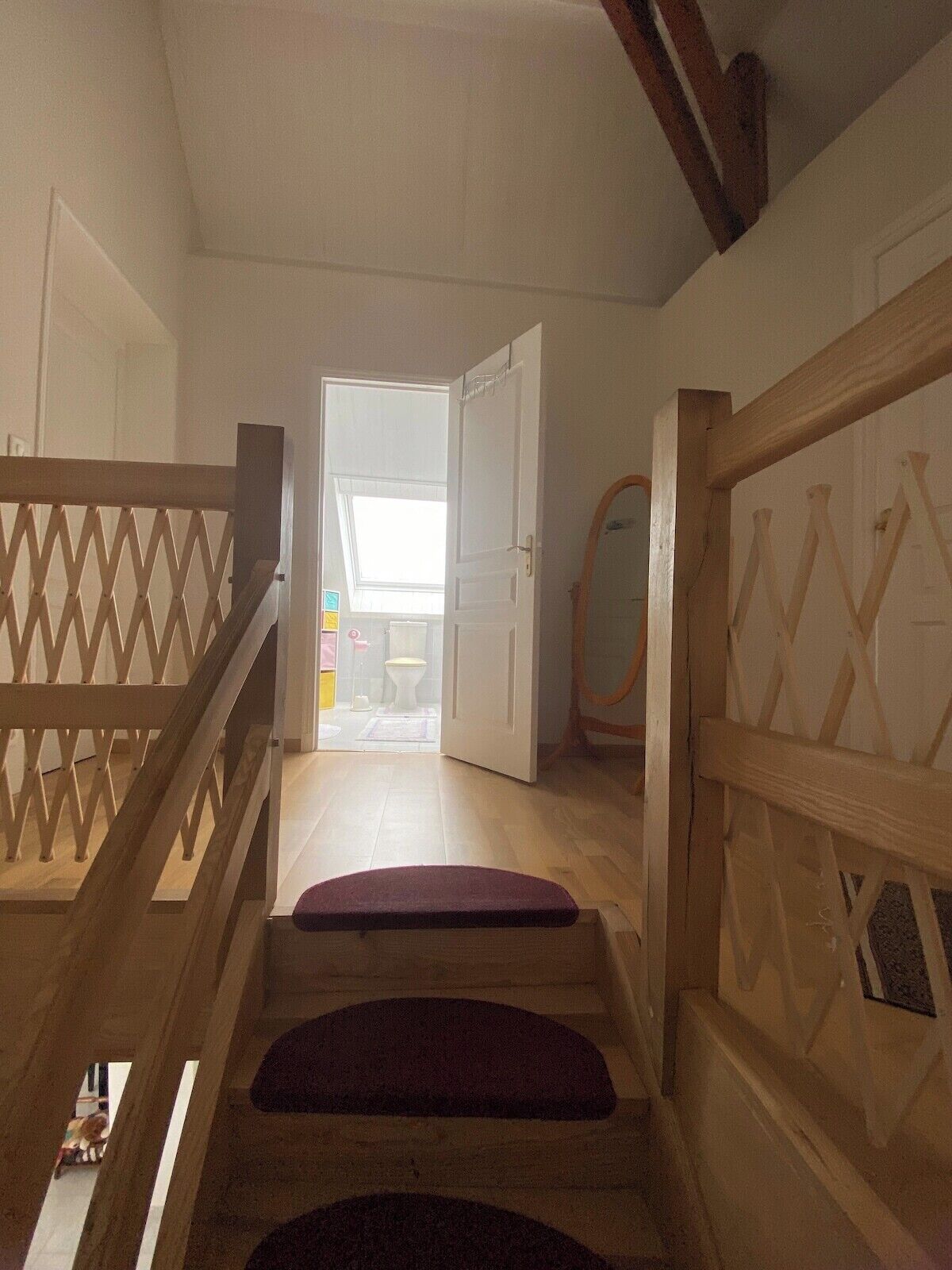 A staircase with wooden railings leading to an open door.