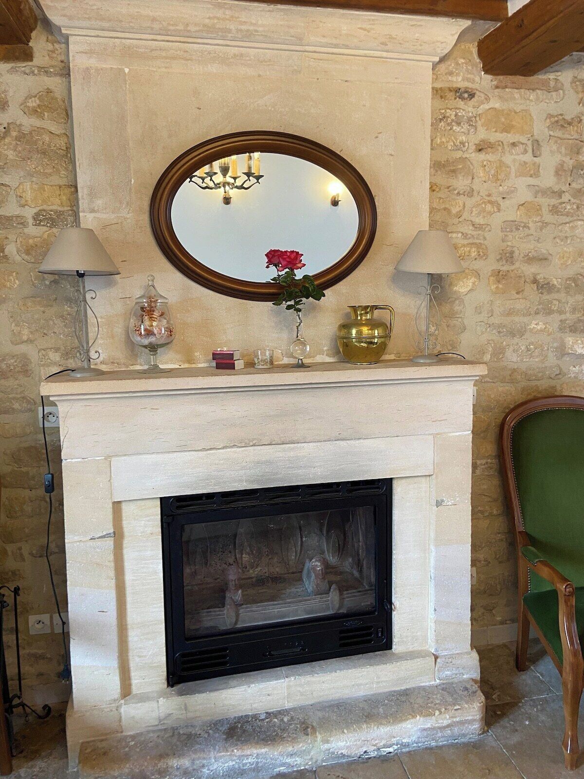 A fireplace with a mirror above it, flanked by two lamps and various decorative items.