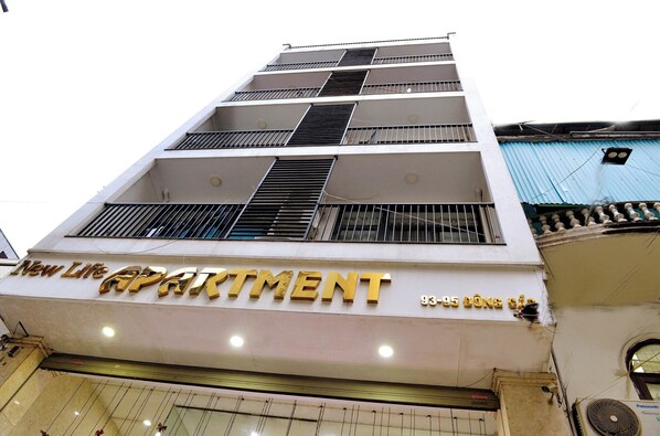 A multi-story building with a sign reading "New Life Apartment" and the address "93-95 Long Chai."