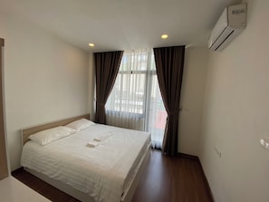 Une chambre d’hôtel avec un lit, des rideaux, une fenêtre et un appareil de climatisation.