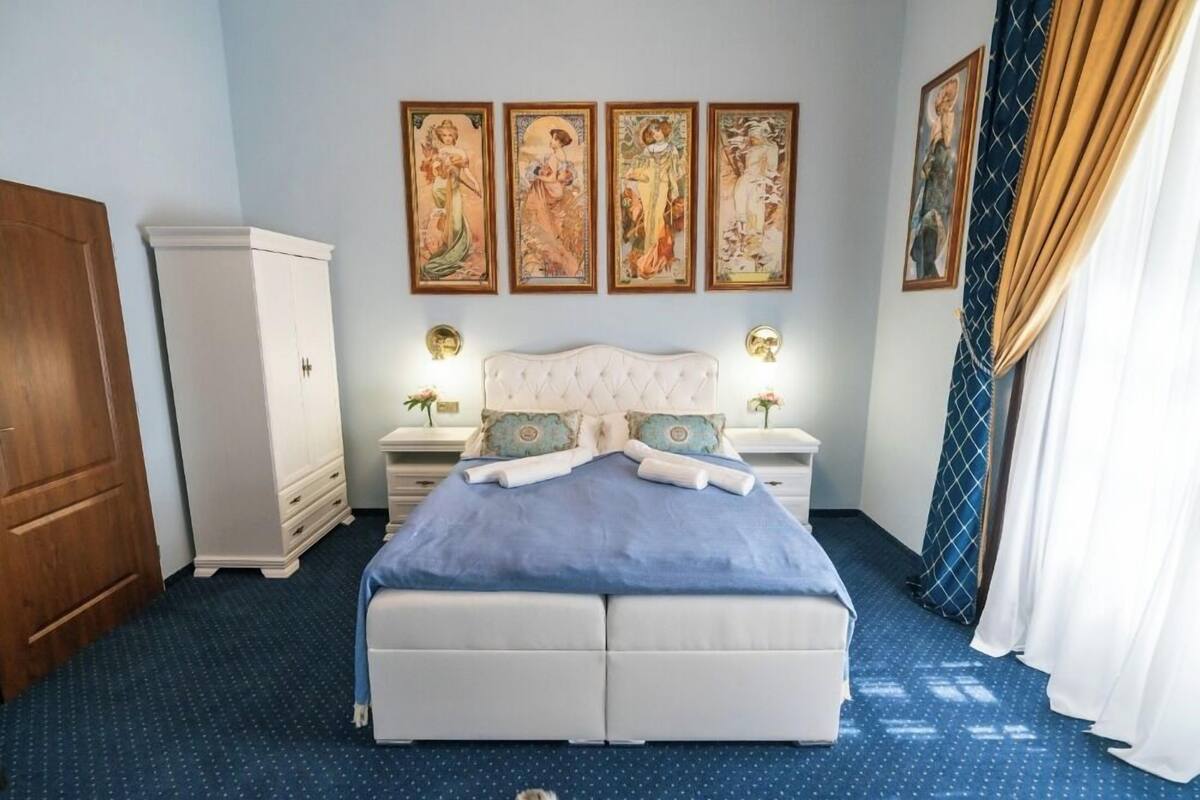 A bedroom with a large bed, a wardrobe, and four framed artworks on the wall.