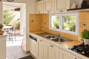 A kitchen with white cabinets, a double sink, and a window with a view of greenery.