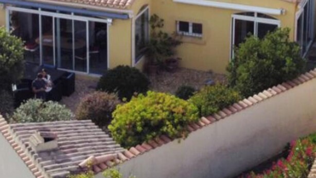 Ein Wohngebäude mit Ziegeldach, Balkon und Garten.