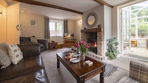 Ein gemütliches Wohnzimmer mit Kamin, einer Couch, einem Couchtisch und einem Essbereich.