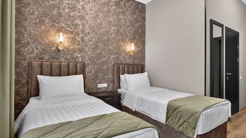 A hotel room with two beds, marble-patterned walls, and a door.