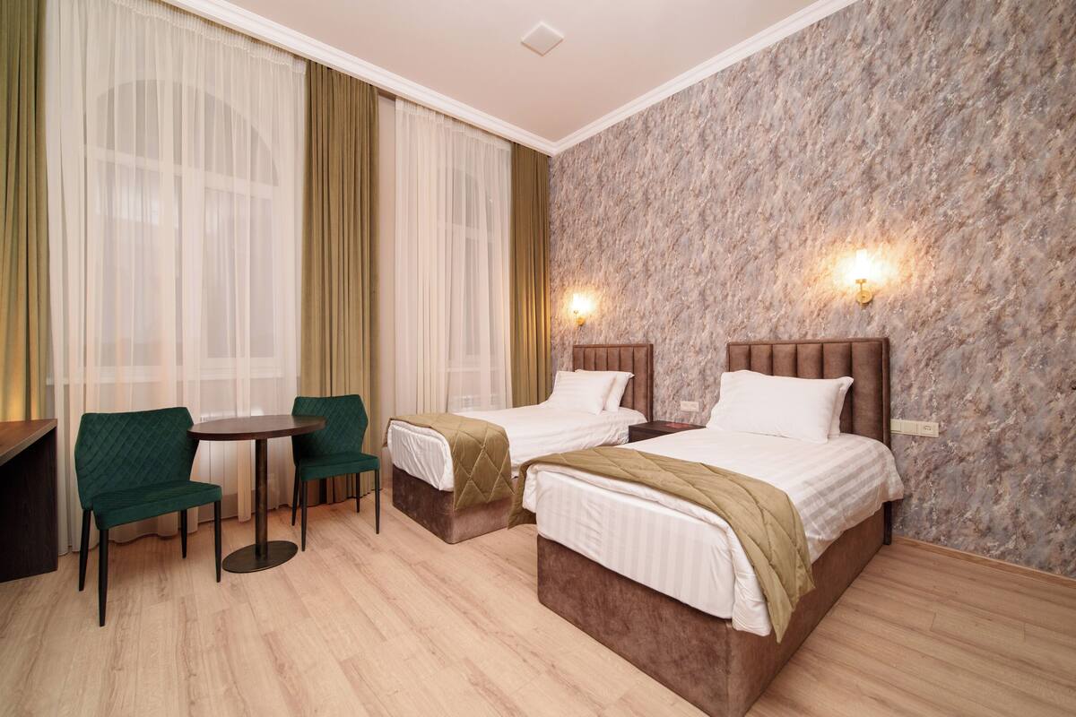 A hotel room with two beds, a small table, and two chairs.